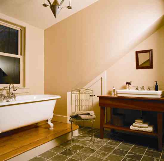 Cathy loves soaking in the reproduction clawfoot tub and gazing out the window. The house’s cabinetmaker, Don Keith, created the sink base from cherry wood. A storage space is tucked beneath the eaves.